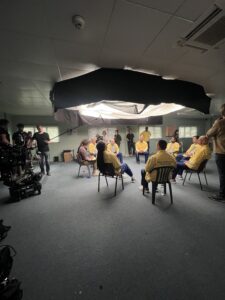 actors sitting in a circle under a light, movie making process