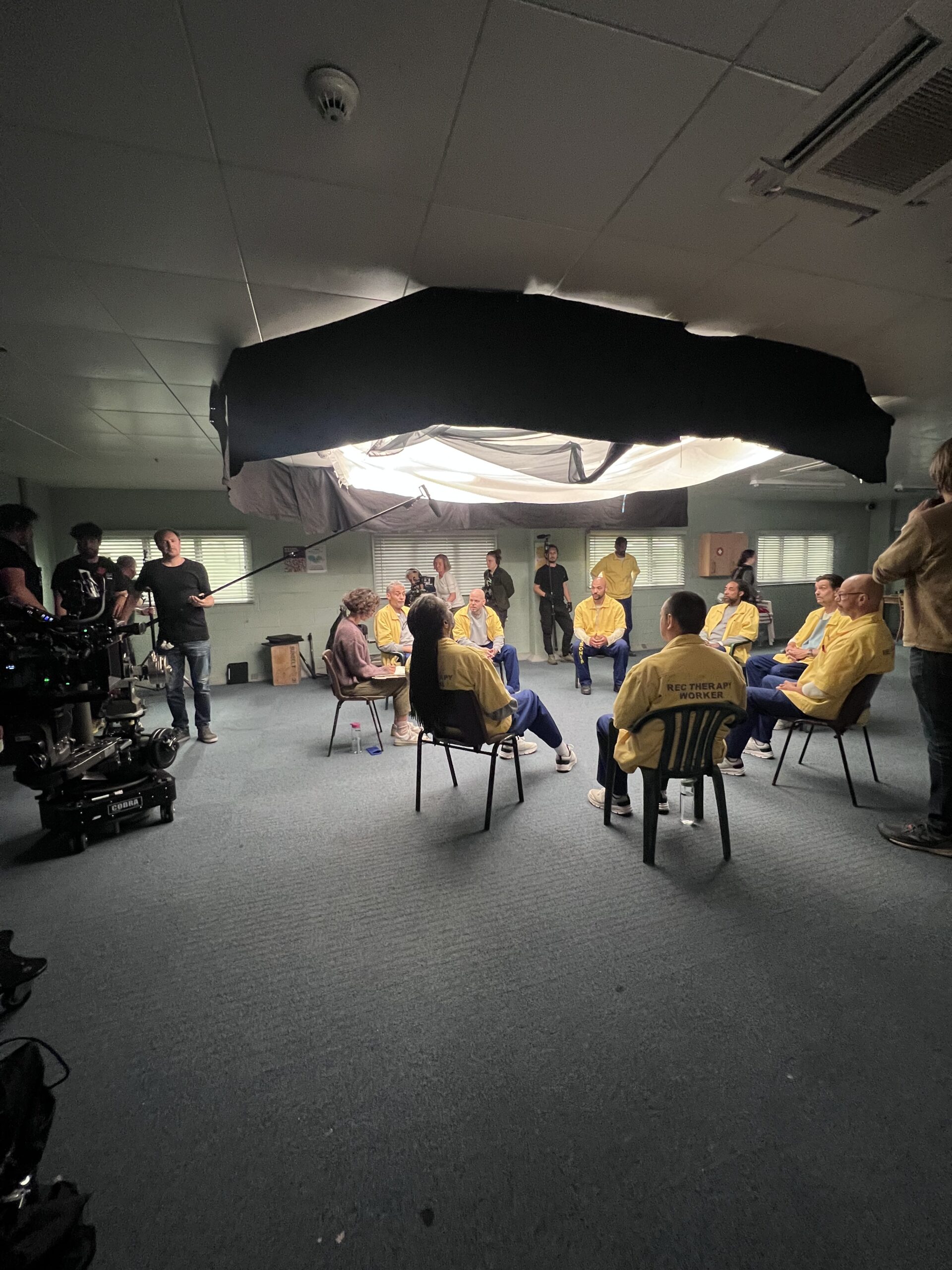 actors sitting in a circle under a light, movie making process